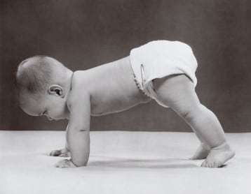 Vintage baby in diaper on hands and feet crawling.