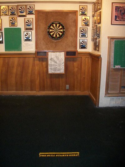 A room with a dart board and darts. The players aim for the bullseye while playing darts.