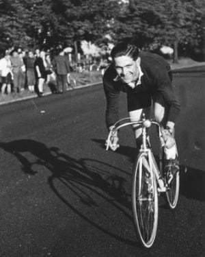 vintage young man riding bicycle with a smiling face in down street.
