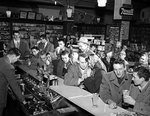 Vintage soda fountain shop full of people.