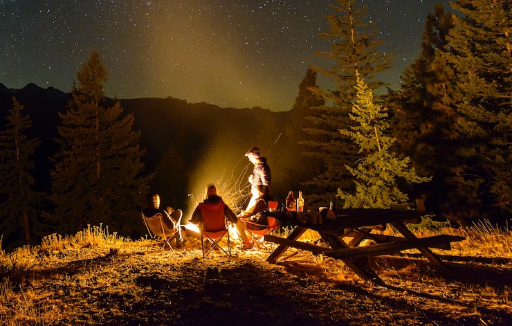 A group of people sitting around a campfire at night, sharing stories and making friends.