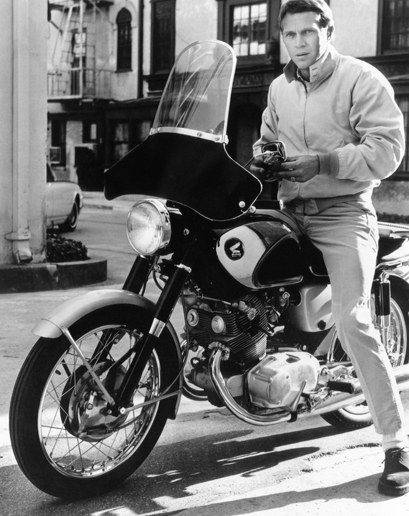 Steve mcqueen sitting on motorcycle.