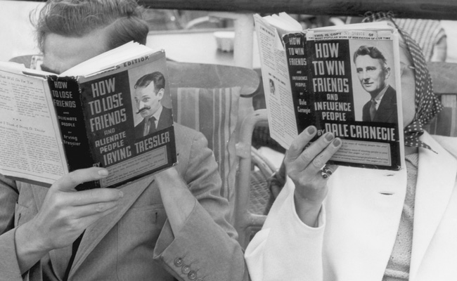 Two individuals on a bench reading books.