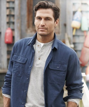 Model wearing layers henley under button up shirt.