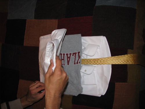 packing dress shirt A man folding t shirt and tie in shirt.