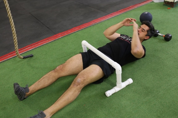 Man crawling on back under the obstacle.