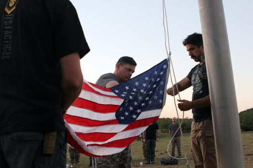 Men raising American flag at flagpole .