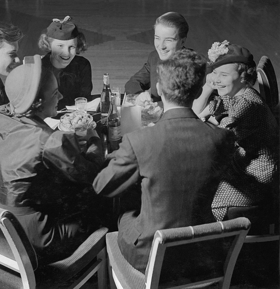 A group of women with good manners sitting around a table.