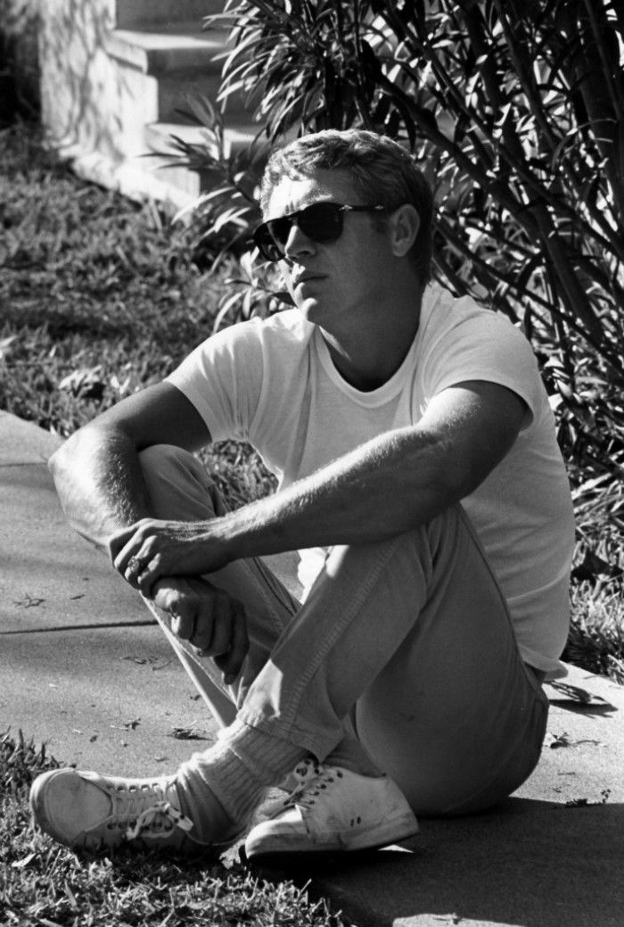 Steve mcqueen sitting on the sidewalk.