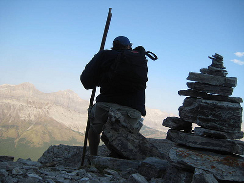 mountain top hiker Hiker on top of mountain sitting on a cairn.