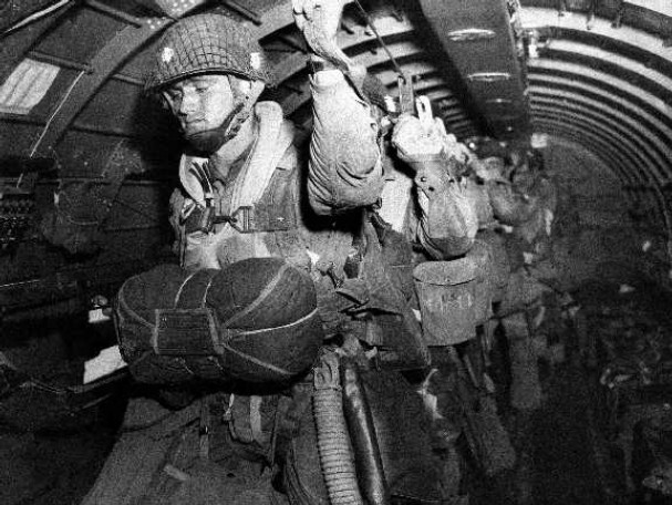 Vintage paratroopers getting ready to jump from airplane.