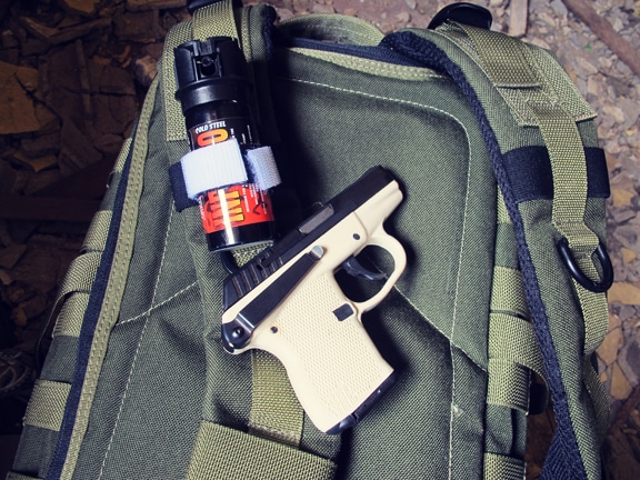 Pepper spray and pistol placed on survival bag.
