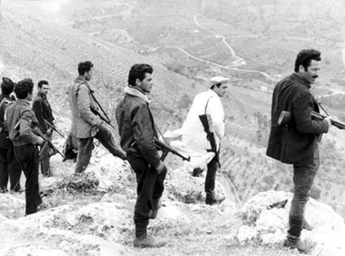 Vintage men with machine guns standing on hill overlooking sicily Italy.