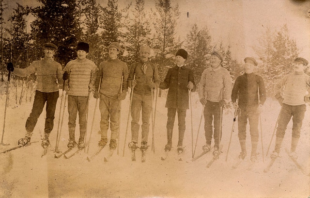Vintage skiers group of men on skies in woods.