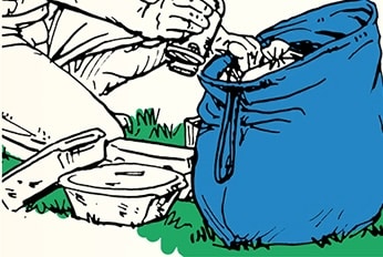 A person crouching on the grass is packing camping food into a large blue bag. Various objects are scattered nearby, showcasing their camping skill to keep animals out of their supplies.