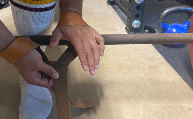 A hand is holding a barbell in a gym for strength training.