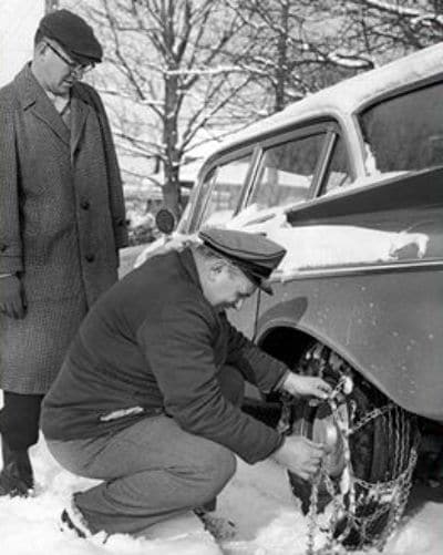 Two men winterizing a car in the snow.