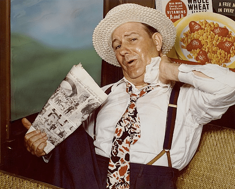 A man wearing a hat carries a handkerchief.