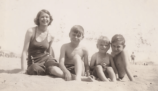 Vintage mother and sons at beach in swimsuits.